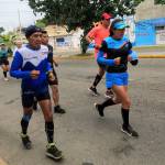 Corredores participando en una carrera en las calles de Oaxaca, encabezados por un veterano con camiseta de Oax Sport y gorro negro, mostrando determinación y espíritu deportivo.