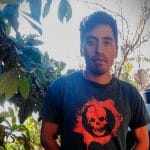 Francisco Soriano con una camiseta negra con un diseño de calavera roja, parado frente a unos árboles.