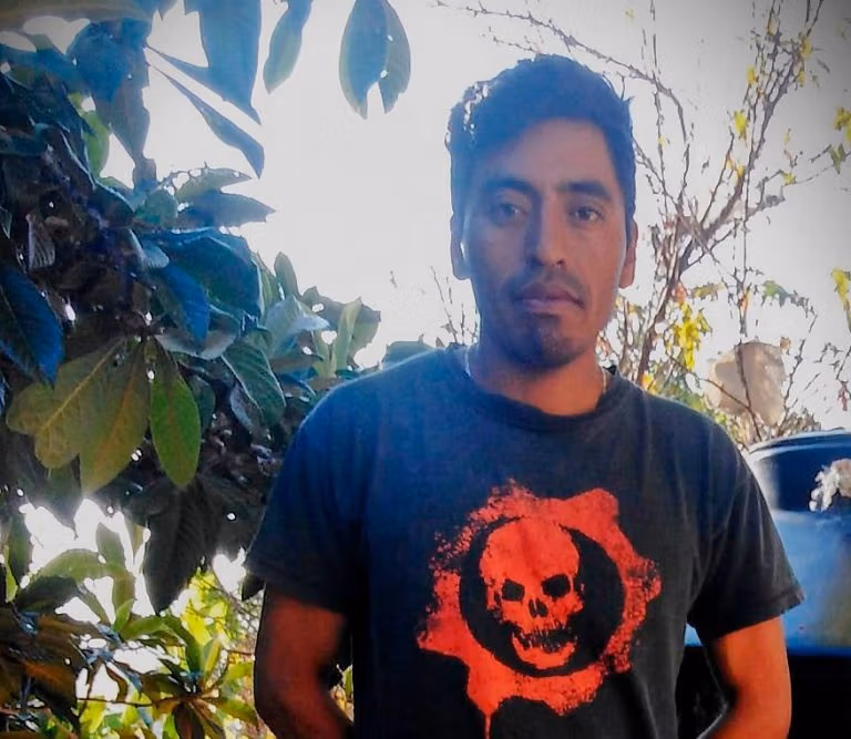 Francisco Soriano con una camiseta negra con un diseño de calavera roja, parado frente a unos árboles.