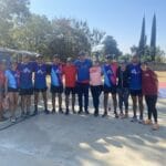 Group of Oax Sport athletes and volunteers posing together outdoors, wearing Oax Sport uniforms and smiling at the camera