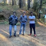 Felipe Arellanes Ruiz, athlete from Santa Catarina Cuixtla, Miahuatlán, Oaxaca, Anthony Ross, consultant and advisor from Nashwauk, Minnesota, and Freddie standing together in a forested area.