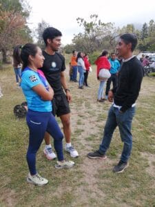 Felipe Arellanes Ruiz and Juan Zurita Victoria talking with a female athlete in a blue shirt at a running event.
