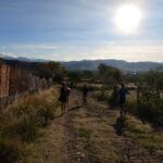 Runners on a dirt path with a scenic view of mountains and the city in the distance, illuminated by the rising sun during the Monte Alban Sunrise Run in Oaxaca.