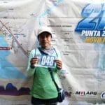 Juana Cruz Garcia holding her race bib number 048 in front of the course map for the 21K Punta Zicatela event in Puerto Escondido, Mexico, November 2023.