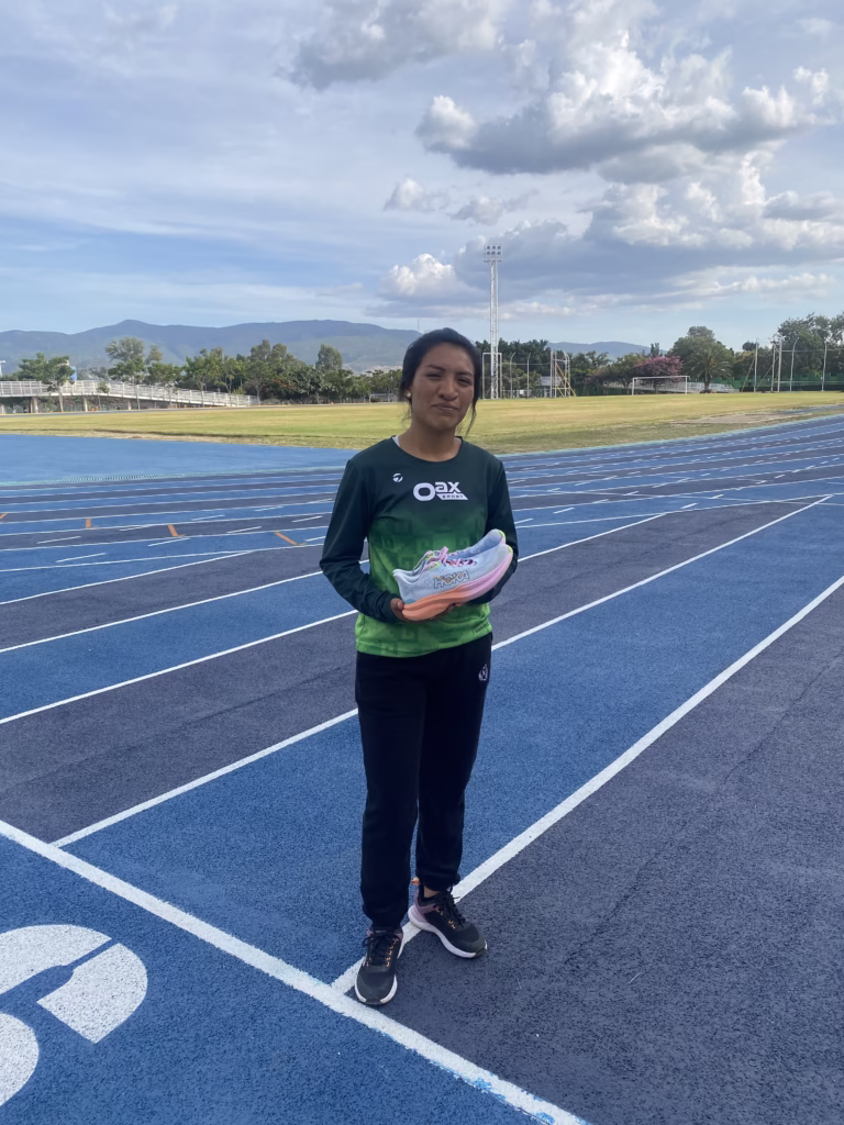 Priscila Santos, atleta oaxaqueña, con tenis donados en una pista azul