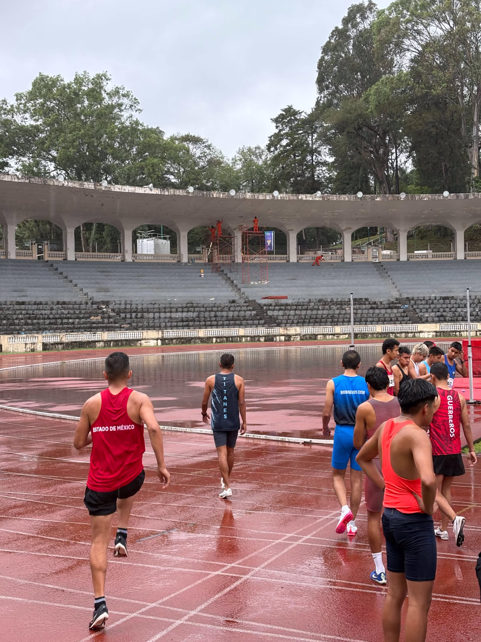 Runners warming up on the soaked red track in Xalapa during the 2025 youth and senior athletics festival.