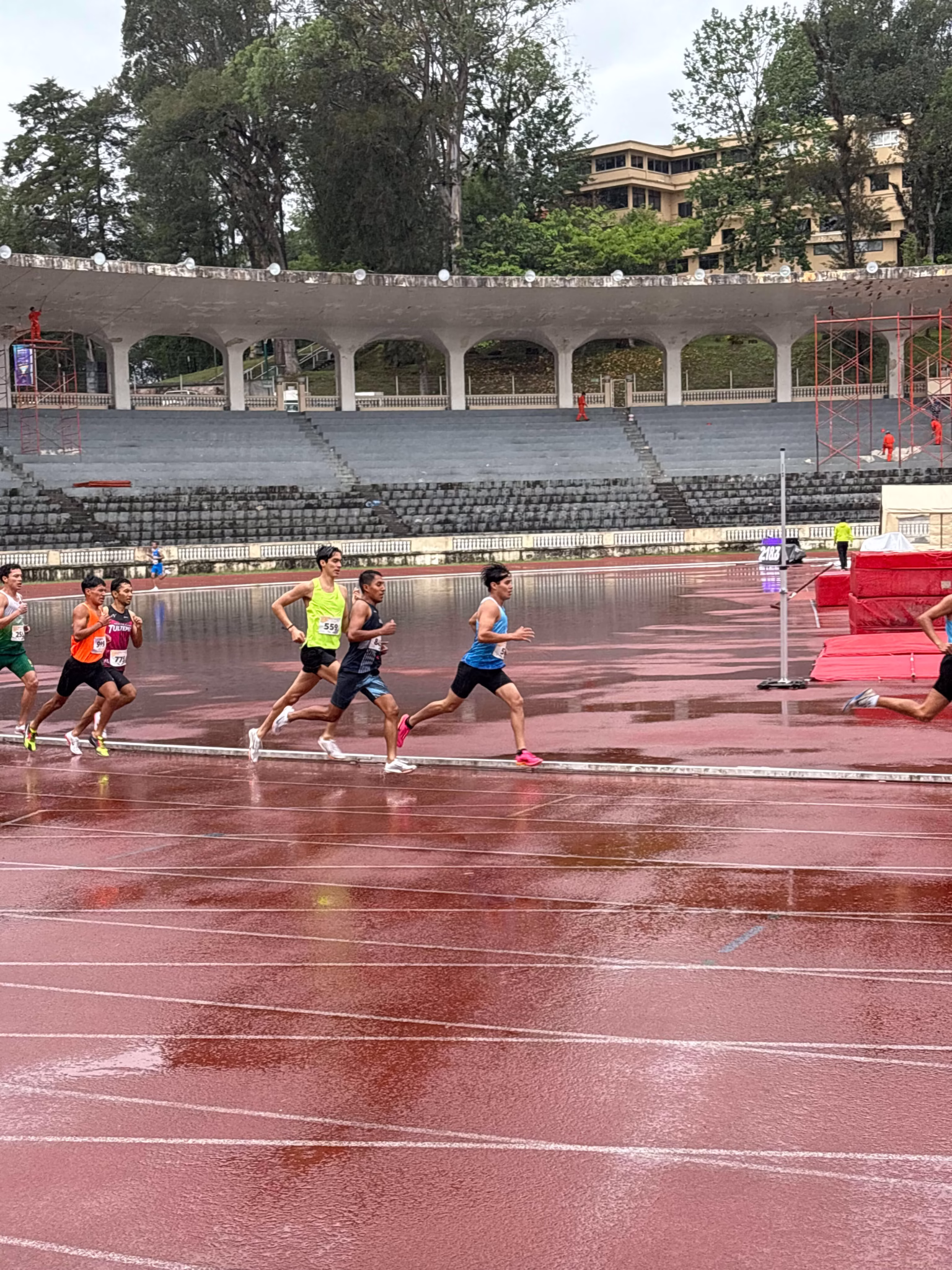 Middle-distance runners spaced out during a rainy race at the Estadio Xalapeño in Xalapa 2025.
