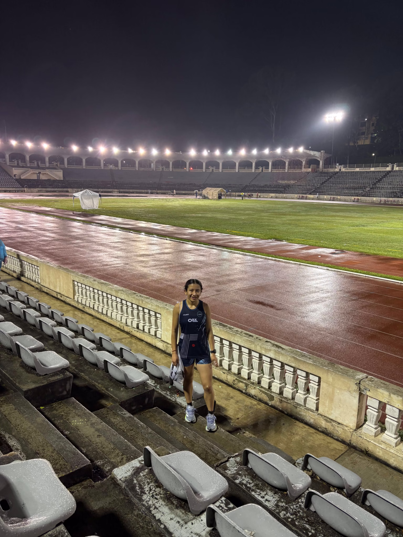 Mane Peña smiling in the stands post-race, wearing her Oax Sport racing uniform