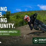 Mountain biker riding a hand-built dirt trail at Senderos Apaztli in Magdalena Apazco, Oaxaca, with Oax Sport branding and a donation callout.