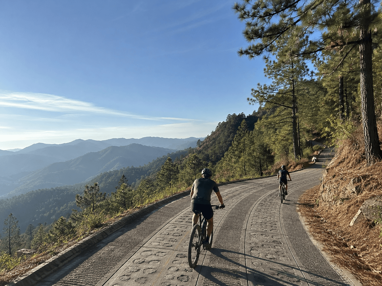 Two riders on a mountain road above the pine forest of the Sierra Norte, Oaxaca