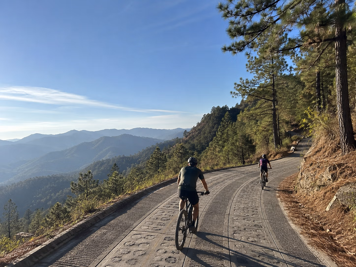 Two riders on a mountain road above the pine forest of the Sierra Norte, Oaxaca