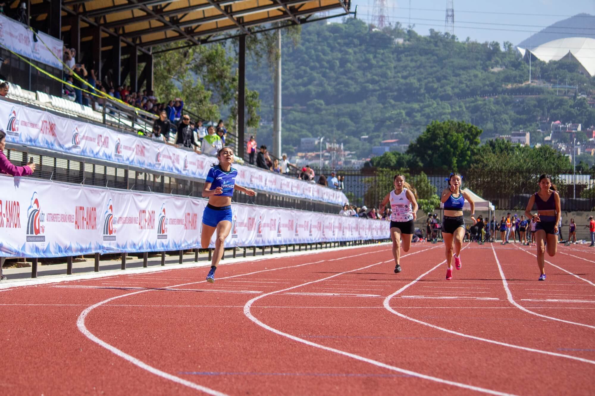 A Titanes relay runner holds the baton during the Festival Atlético Autotransportes Avendaño Morales 2026 in Oaxaca.