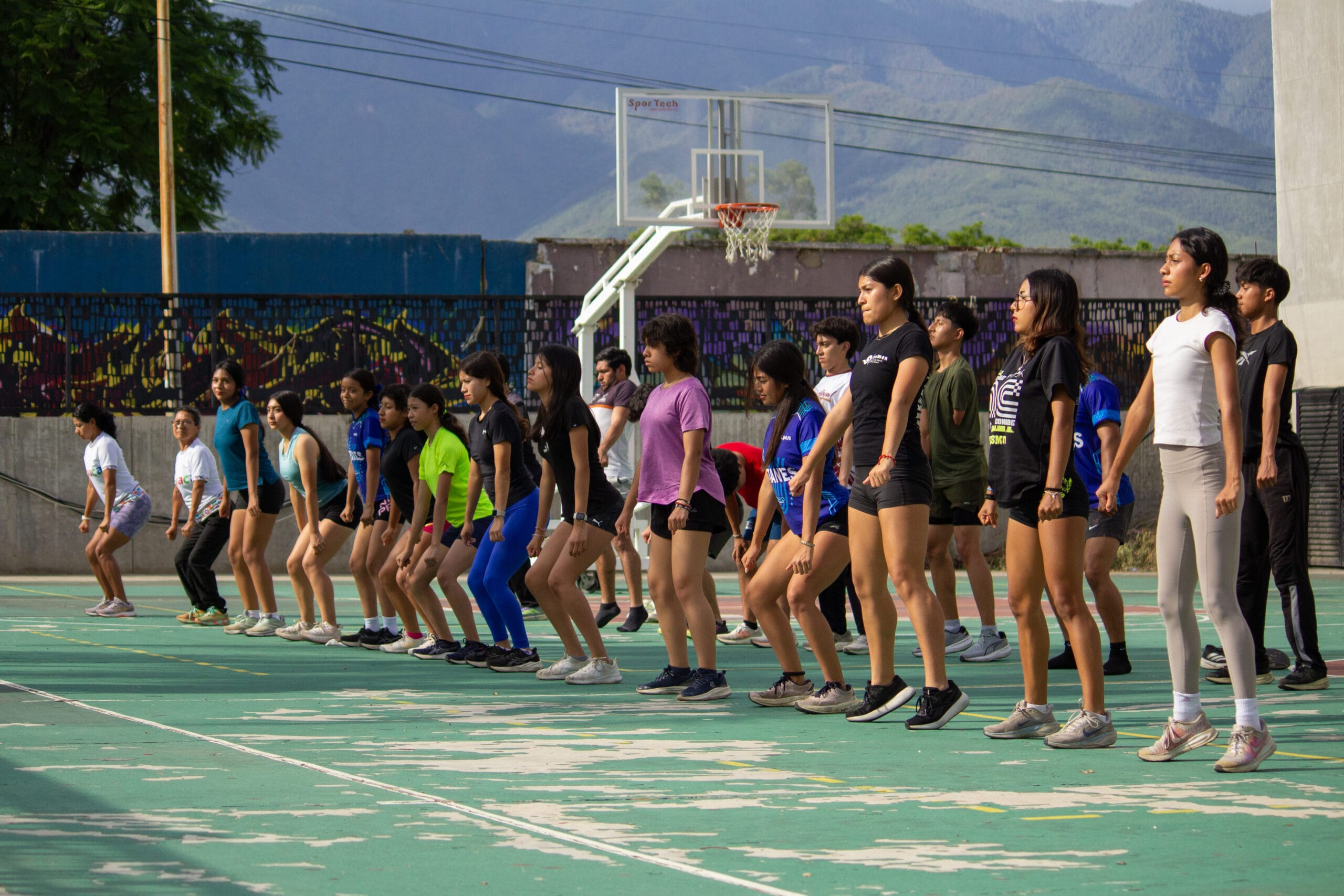 Atletas realizando juntos un ejercicio de fuerza funcional al aire libre en el Complejo Deportivo Hermanos Flores Magón.