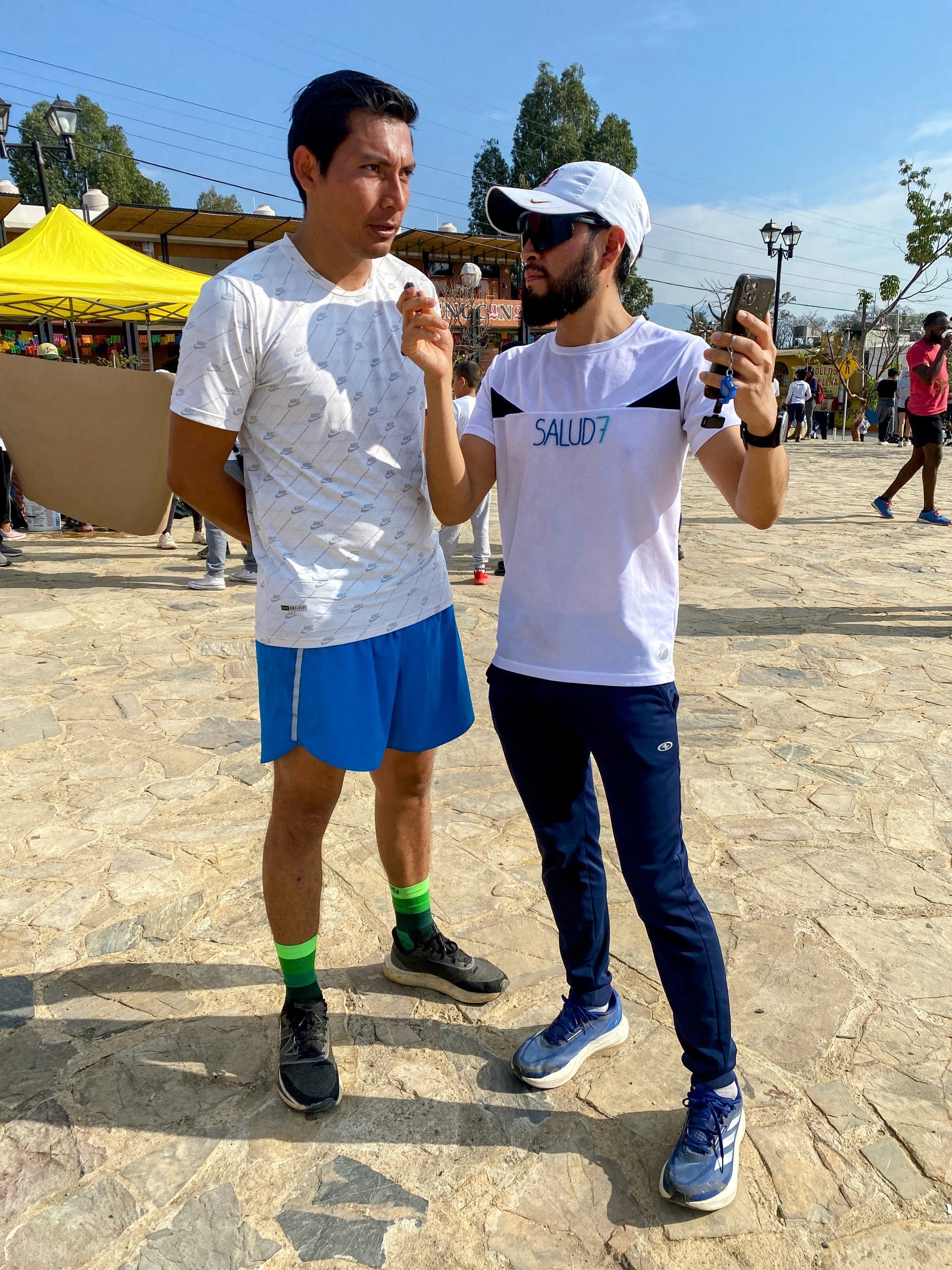 Dos jóvenes grabando una entrevista a un atleta con un teléfono en un evento de Oax Sport en Oaxaca