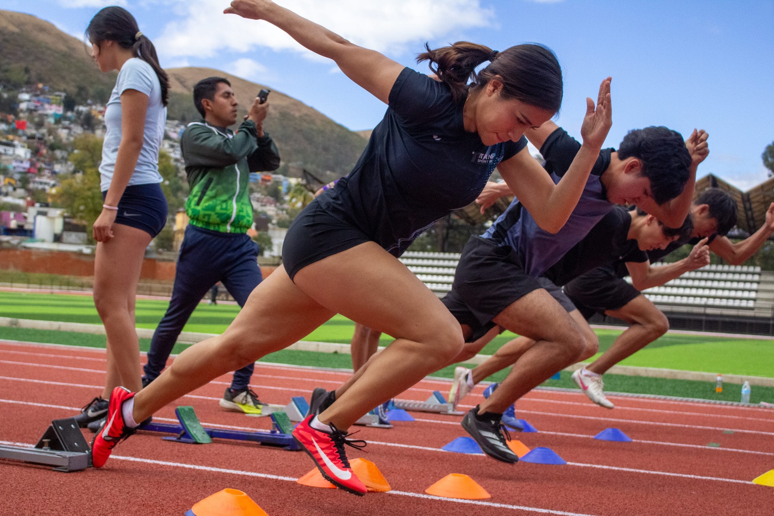 Group of girls driving out of the starting blocks during a sprint training session on the track in Oaxaca
