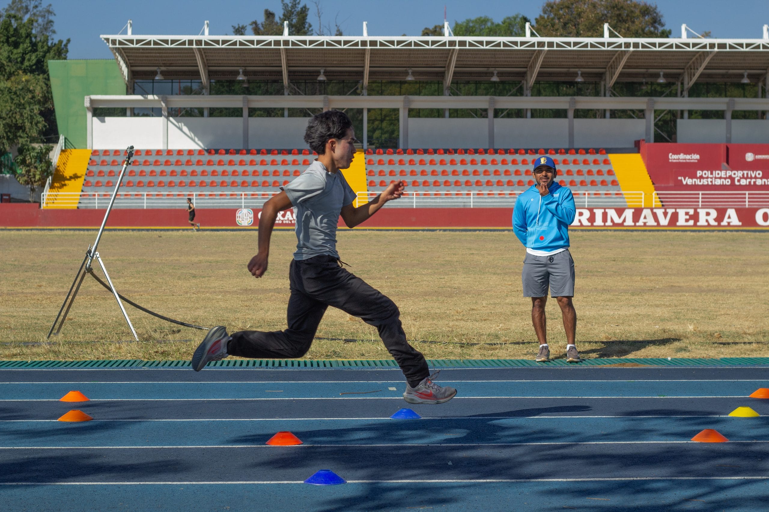Young athlete sprinting past training cones on the track during an Oax Sport youth skills session in Oaxaca