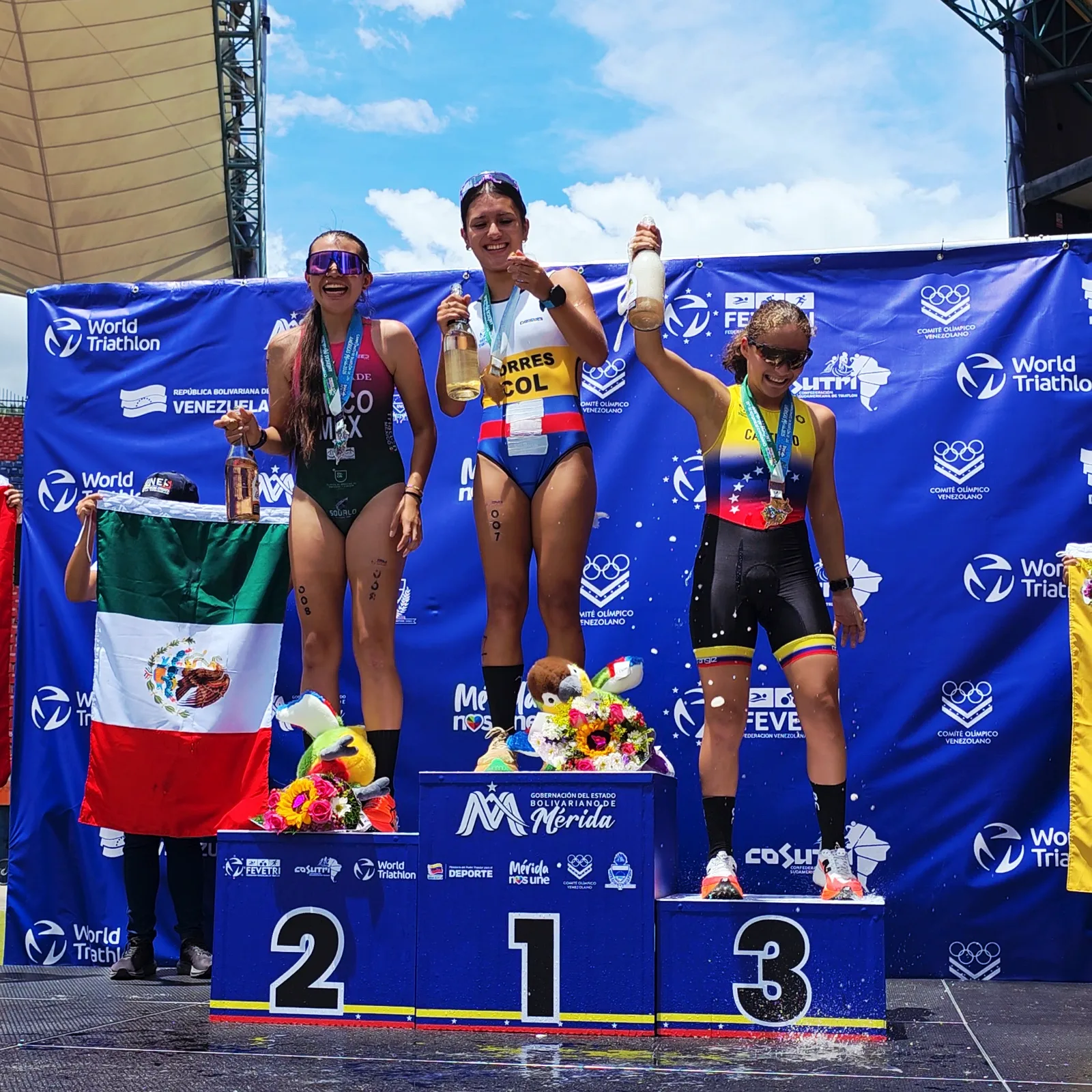 Carolina Cinco on the second-place podium at the 2026 Americas Duathlon Championships in Mérida, holding the Mexican flag.