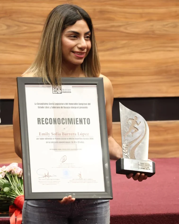 Emily Barrera sostiene su diploma y trofeo del Premio Estatal al Mérito Deportivo dentro del Congreso de Oaxaca.